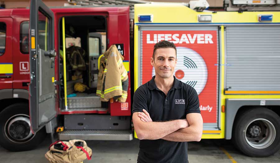 Greg Lessons, London Met alumnus, stands in front of a fire engine