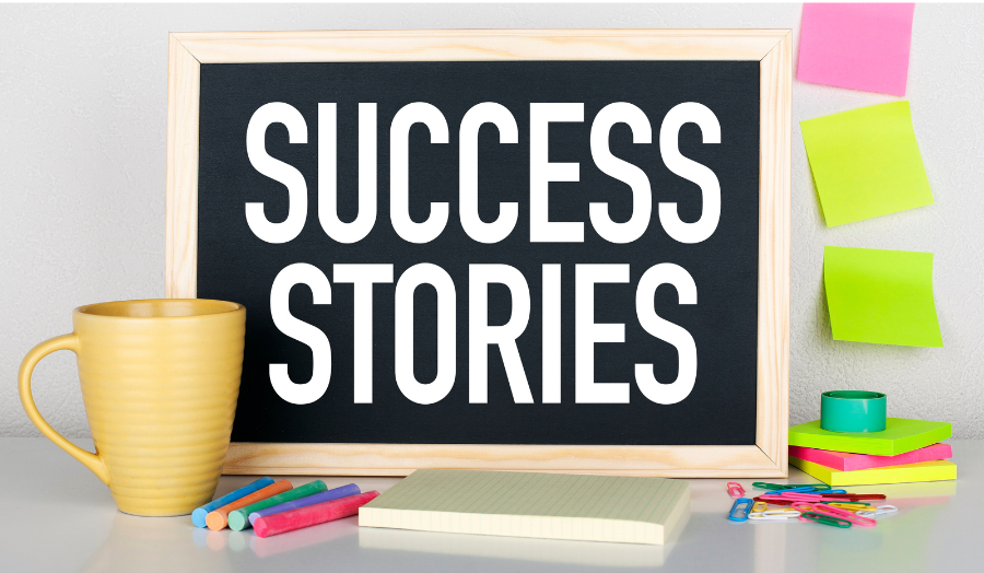 Across the blackboard, surrounded by office supplies, is written: Success Stories.