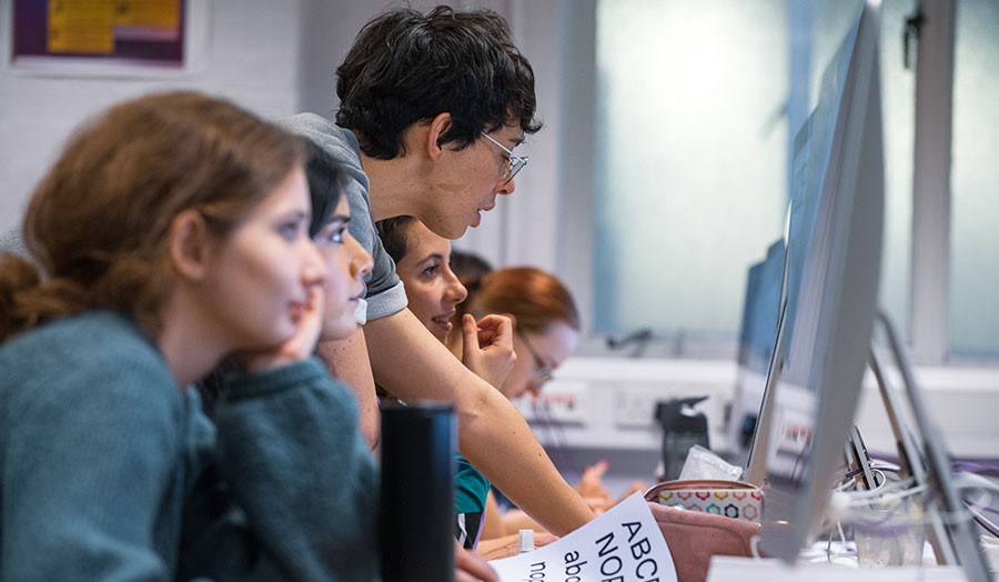 Female lecturer explaining something on computers to students