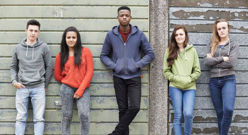 Four young people standing in front of a wall.