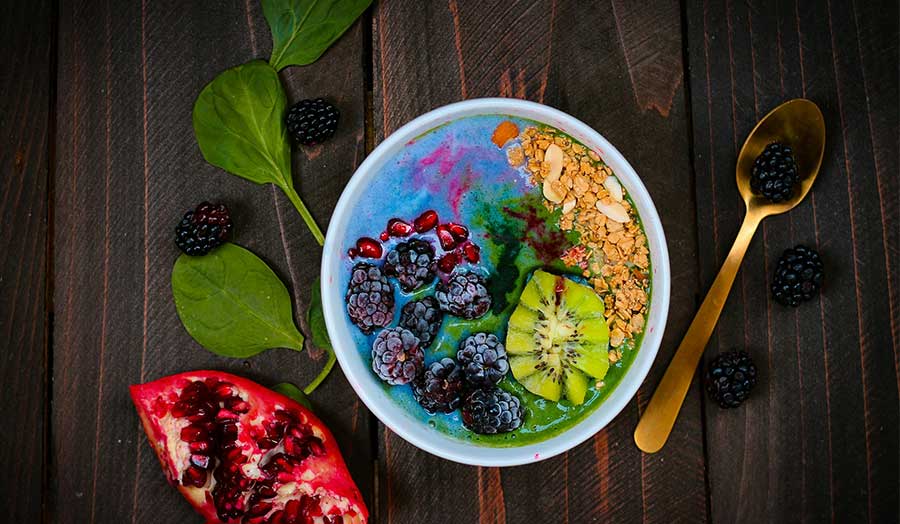 A brightly coloured smoothie, berry, and granola bowl