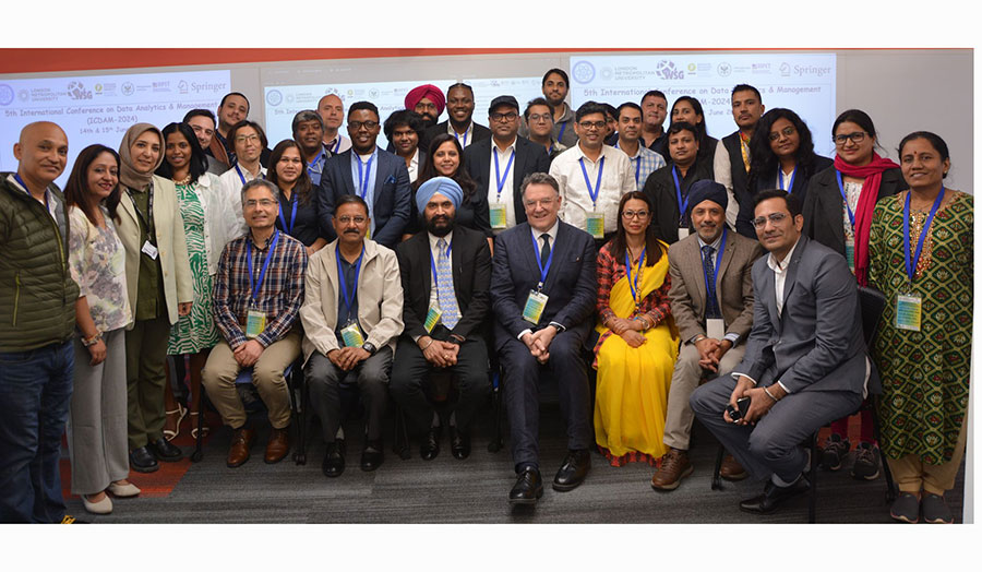 A mixed group of academics sitting and standing in front of the camera