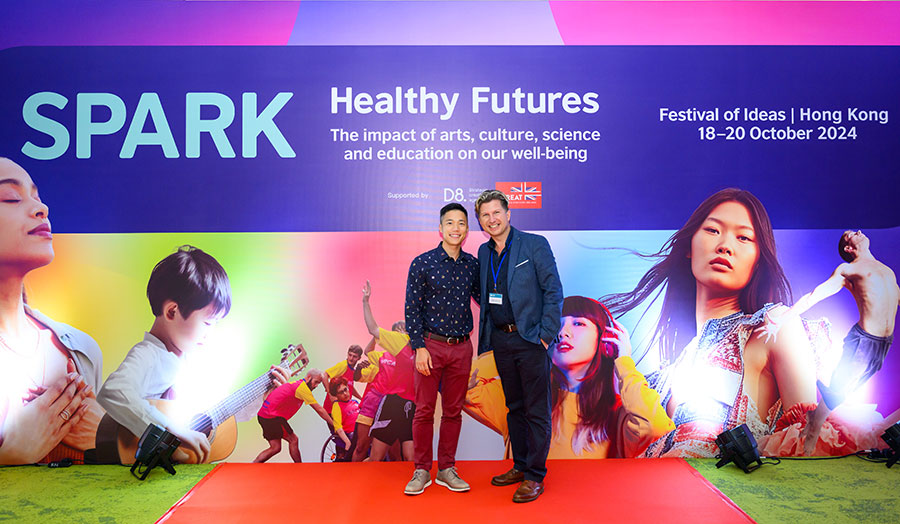 Two men standing in front of the colourful banner