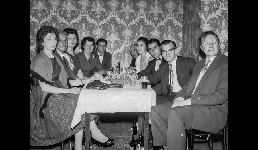 A group of ten people sit together around a table in formal clothing