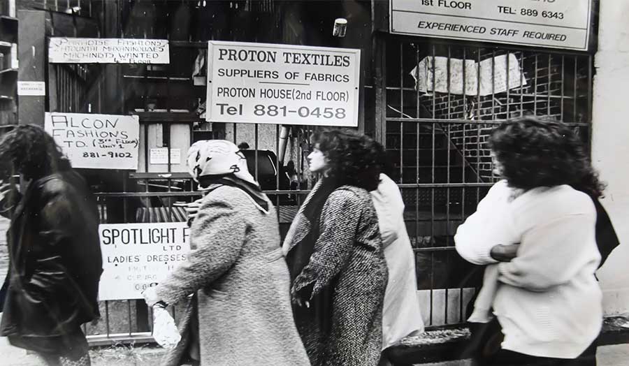 A group of women walk past signs for manufacturing and textile companies