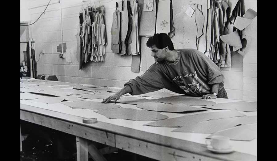 A man lays out pattern pieces to cut fabric for clothing