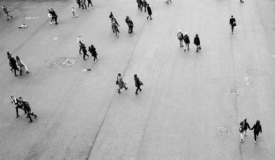 An aerial shot of several people walking in an otherwise empty urban setting