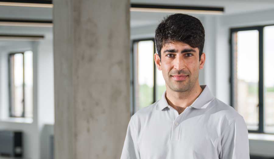 Rohullah pictured in a casual shirt with concrete pillar in the background